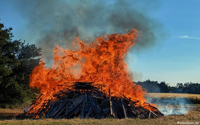 Ein Feuer mit viel Holz auf einer Freifläche: Das Johannisfeuer der Kolpingsfamilie Monheim.